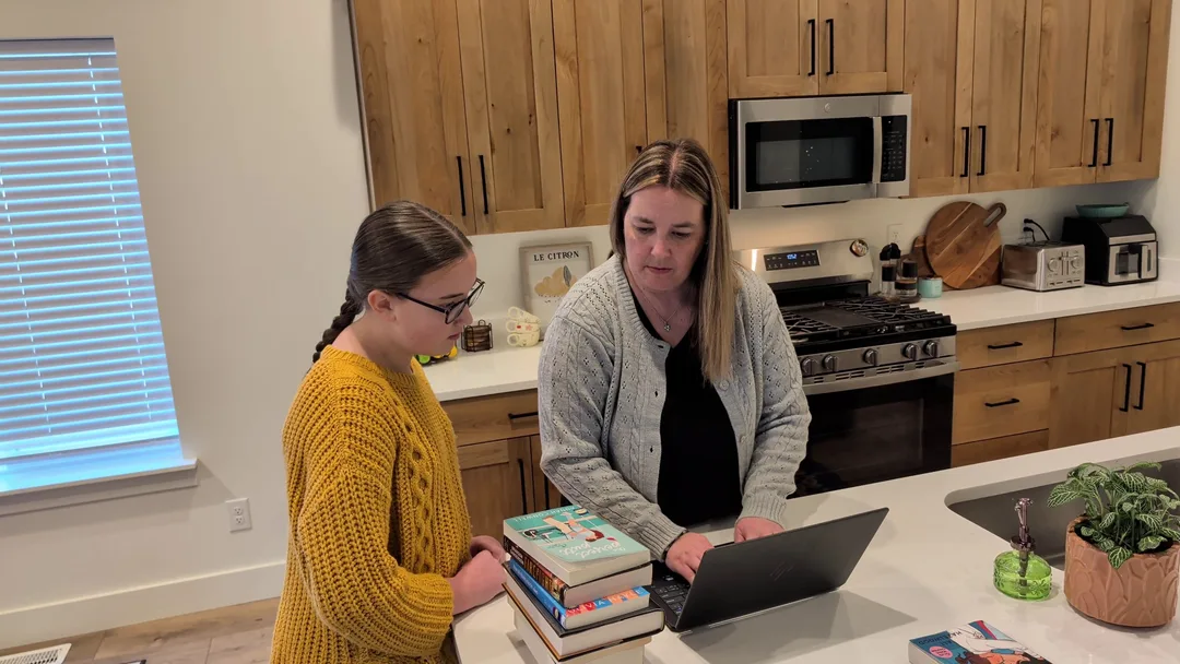A mother and daughter checking a book's rating on a laptop in their kitchen
